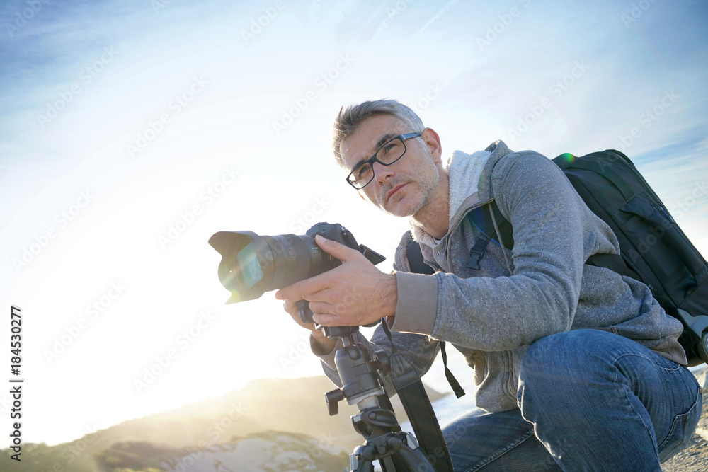 Portrait of photographer taking pictures in natural landscape - obrazy, fototapety, plakaty 