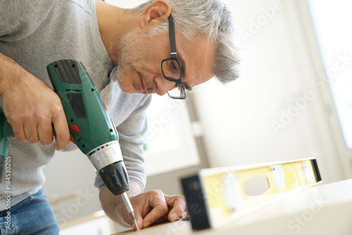 Quadro em tela Man assembling DIY furniture using electric drill