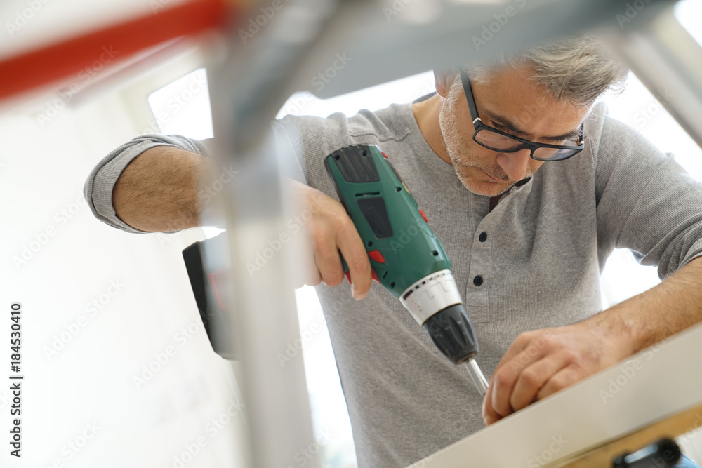 © goodluz - Man assembling DIY furniture using electric drill © goodluz - Man assembling DIY furniture using electric drill