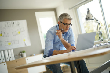 Architect in office working on construction project using laptop