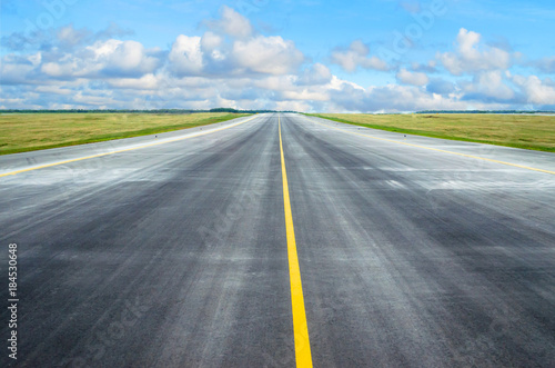 Asphalt road runway with a dividing strip in the horizon. © aapsky