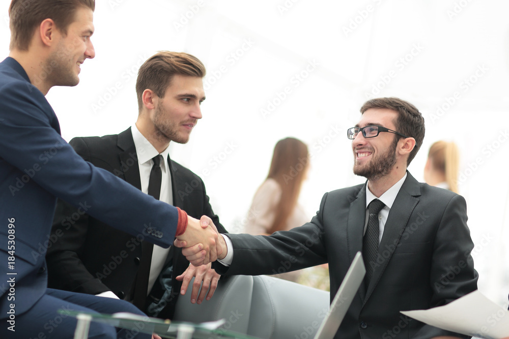 Partners concluding deal and shaking hands in the presence of team members Partners concluding deal and shaking hands in the presence of team members