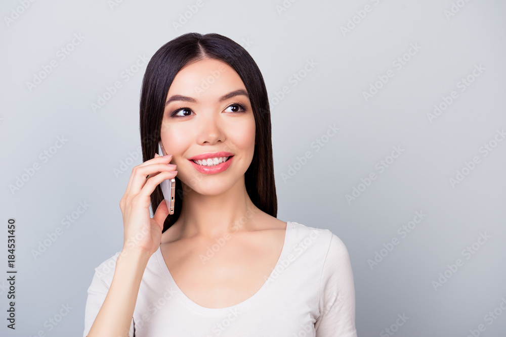 Close up portrait of pretty, attractive, smiling woman in casual outfit speaking on the smart phone with client, standing over grey background Close up portrait of pretty, attractive, smiling woman in casual outfit speaking on the smart phone with client, standing over grey background