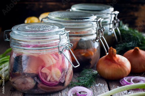 Variants of pickled herring in glass jars, selective focus photo