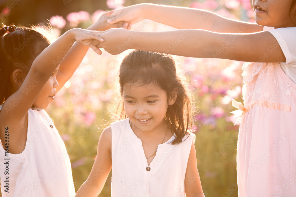 Obraz premium Children having fun to play together in the cosmos flower field in summer time with sunlight