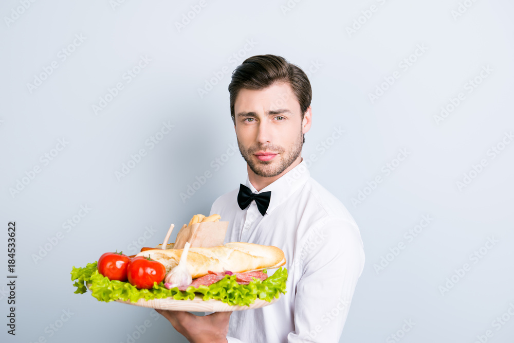 Handsome confident and smiling waiter is ready to take your order! Garcon clothed in white pure formal wear is holding a tray with an antree on it, he is isolated on grey background Handsome confident and smiling waiter is ready to take your order! Garcon clothed in white pure formal wear is holding a tray with an antree on it, he is isolated on grey background