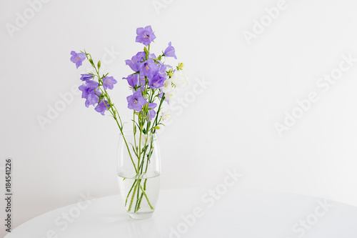 Flowers bells in a glass vase stand on a white round table