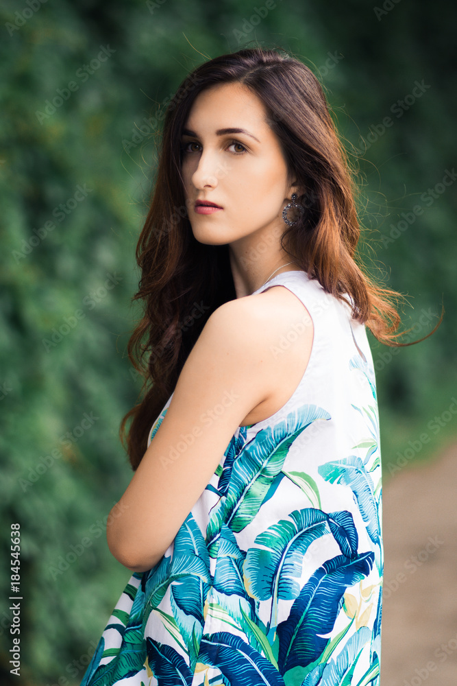 Naklejka premium Sunny positive portrait of sexy stunning girl in short colorful dress having fun on the street