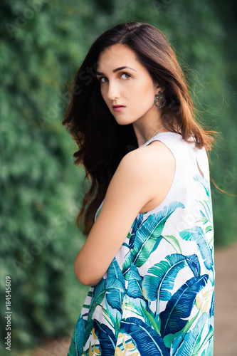 Sunny positive portrait of sexy stunning girl in short colorful dress having fun on the street