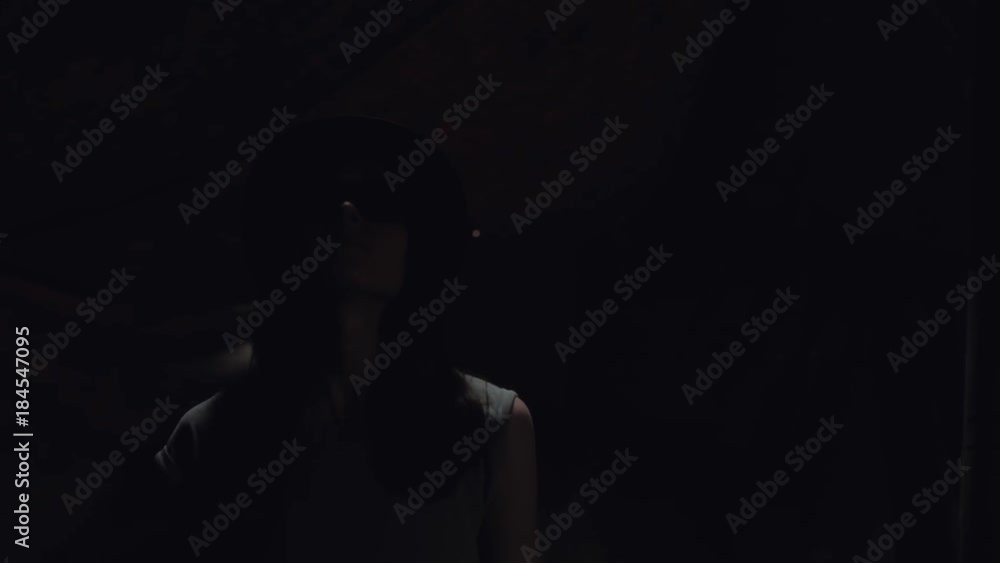 female with a hat and sunglasses going in a dark cave looking up at the light in the sky female with a hat and sunglasses going in a dark cave looking up at the light in the sky