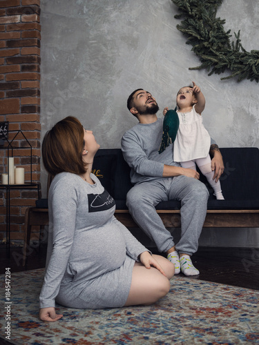 Little girl and his parents kissing. Pregnant woman. So happy family