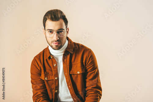 portrait of handsome young man looking at camera isolated on beige