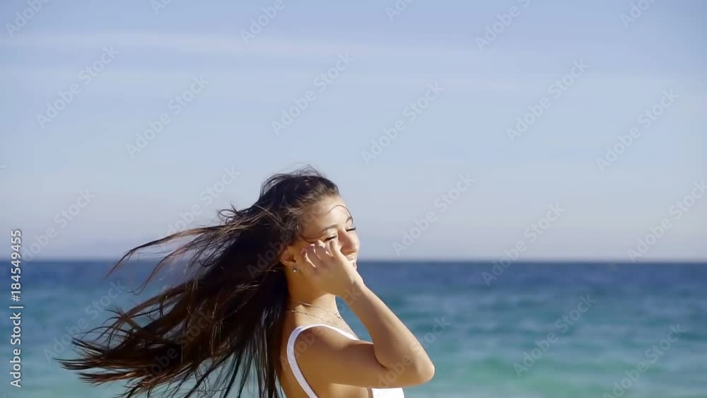 cheerful young brunette is whirling on a beach in sunny summer day on a vacation, smiling and raising hands cheerful young brunette is whirling on a beach in sunny summer day on a vacation, smiling and raising hands