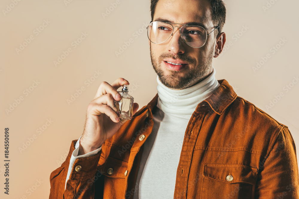 portrait of stylish young man applying perfume isolated on beige Stock ...