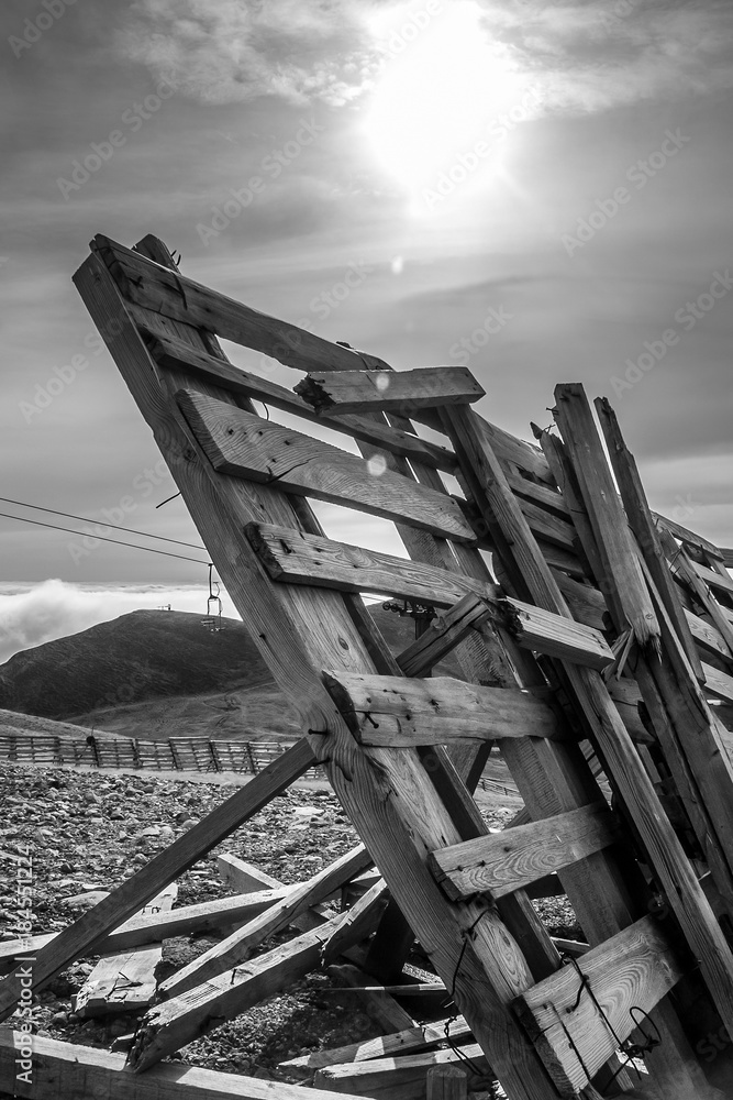 A tranquil mountain scene with clouds cover and fence on a hill. Black and white