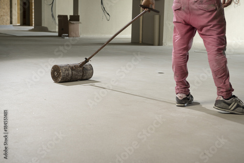 Manual worker pressing vinyl floor with pust roller. 