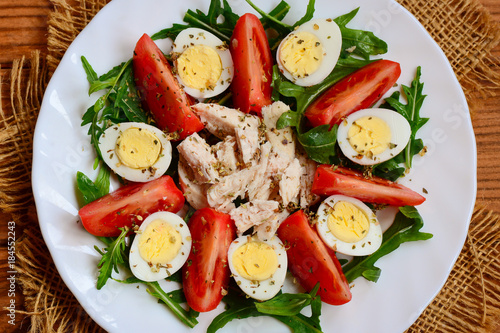 Chicken breast, tomatoes, quail eggs and arugula salad. Healthy and tasty salad for lunch or dinner. Top view