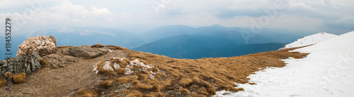 End of the road on mountain summit.Other mountains and heavy overcast sky in the background