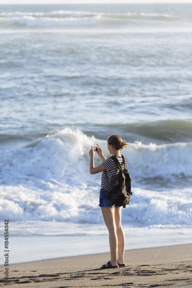 Indonesia, Bali, young woman taking cell phone picture on the beach Indonesia, Bali, young woman taking cell phone picture on the beach