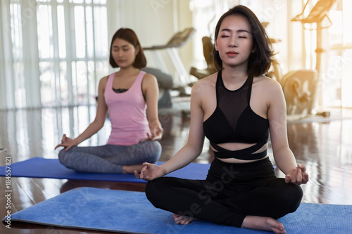 Two healthy woman making yoga in the gym