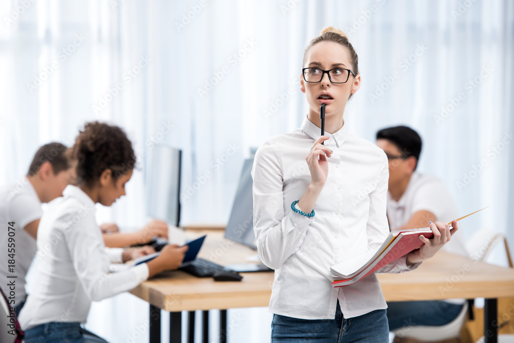 young pensive caucasian student girl in classroom with friends young pensive caucasian student girl in classroom with friends