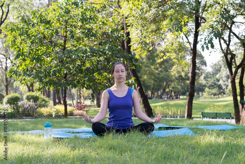 Woman on a yoga mat to relax in the park outdoor, Concept of healthy lifestyle and relaxation.. © xreflex