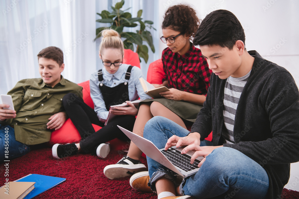 multicultural teenagers studying with laptop and exercise books multicultural teenagers studying with laptop and exercise books