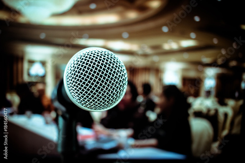 Microphones on front stage in seminar room, for talking speech in conference hall light with microphone and keynote, blur light of audiences meeting room background, vintage tone
