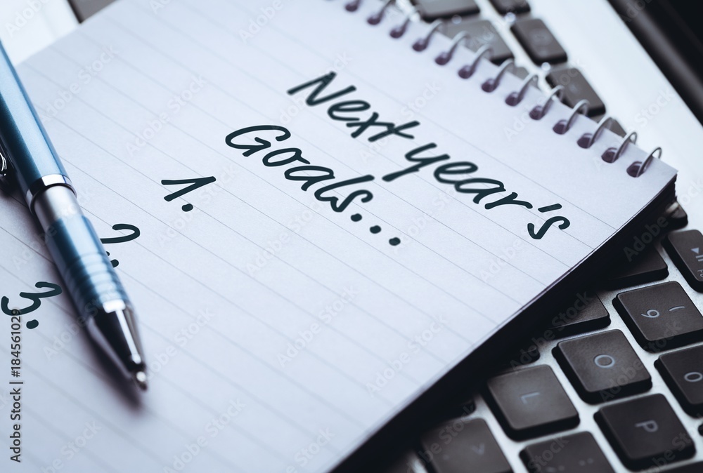 Top View of new years resolution written on notepad with pen on side on laptop Top View of new years resolution written on notepad with pen on side on laptop