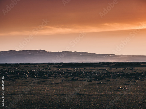 scenery with black sand, rocks and mountains at sunset, Iceland