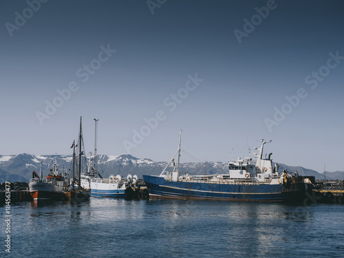 Fishing boats and snowy mountains in Husavik harbour, Iceland © LIGHTFIELD STUDIOS
