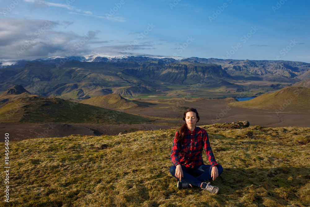 meditate on a background of mountains. Young woman alone with nature