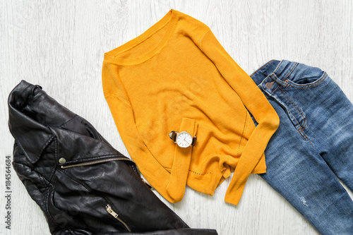 Orange sweater, watch, black jacket and jeans. Fashionable concept