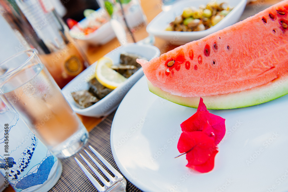 Turkish raki or greek ouzo with traditional appetizers and watermelon and bougainvillea flower, Turkish or greek restaurant dinner dining table Turkish raki or greek ouzo with traditional appetizers and watermelon and bougainvillea flower, Turkish or greek restaurant dinner dining table