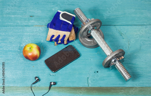 Sport items bottle, dumbbells, gloves on the sport flooring