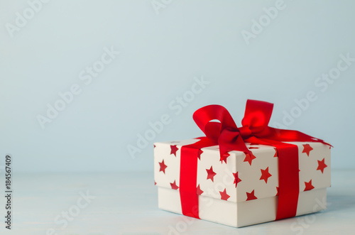 White gift box with red star pattern and red ribbon bow