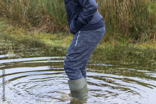 Man with water proof boots wading through water