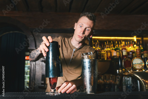 A man bartender makes beautiful alcoholic cocktails. Creation of alcoholic cocktails at the bar.