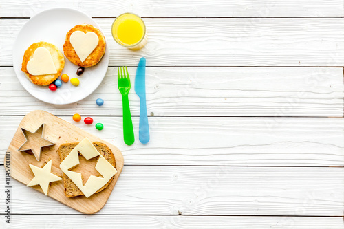Funny breakfast for children. Sandwiches with cheese in shape of stars and hearts. White wooden background top view copyspace