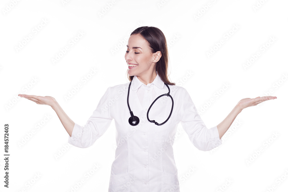 Attractive confident young medic woman are compares some stuff over white background. Copyspace. Attractive confident young medic woman are compares some stuff over white background. Copyspace.