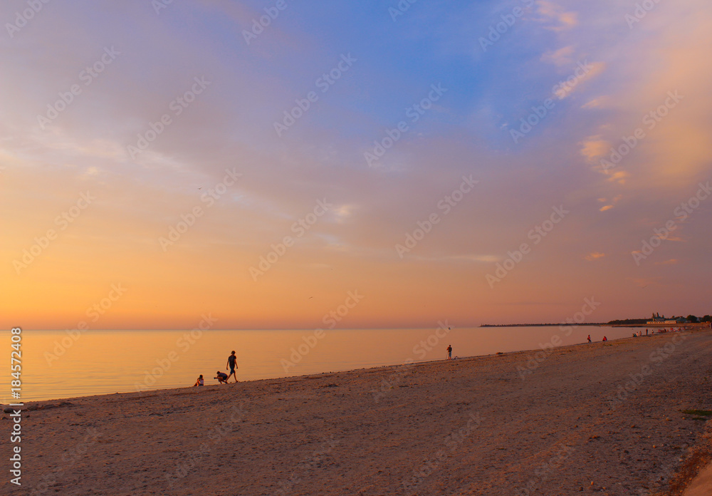 A beautiful sunset on the beach on a calm summer evening, the smooth surface of the windless sea reflects the delightful colors of the sky as a big mirror. A beautiful sunset on the beach on a calm summer evening, the smooth surface of the windless sea reflects the delightful colors of the sky as a big mirror.