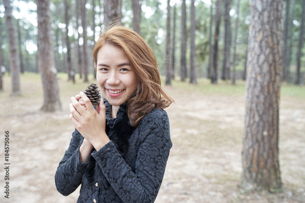 Beautiful asia woman with brown hair holding pine cones in her hand Beautiful asia woman with brown hair holding pine cones in her hand