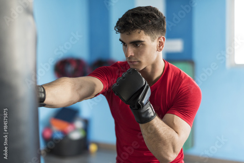 Boxer young man in gym training with punching bag © FotoAndalucia