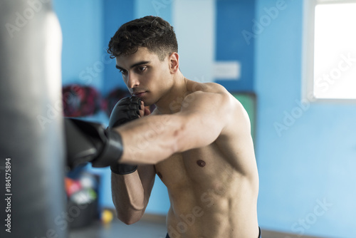 Fototapeta Naklejka Na Ścianę i Meble -  Boxer in gym training with punching bag