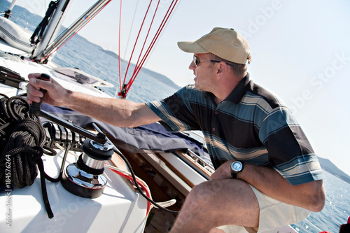 Fotografija Man hoisting sail on yacht