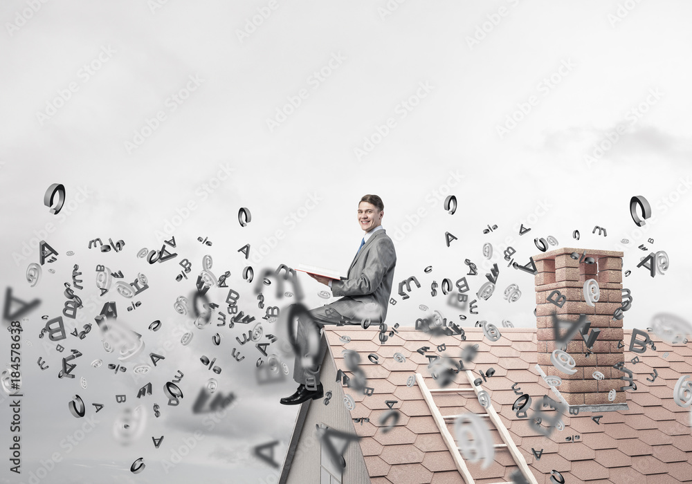 Man on brick roof reading book and symbols flying around Man on brick roof reading book and symbols flying around