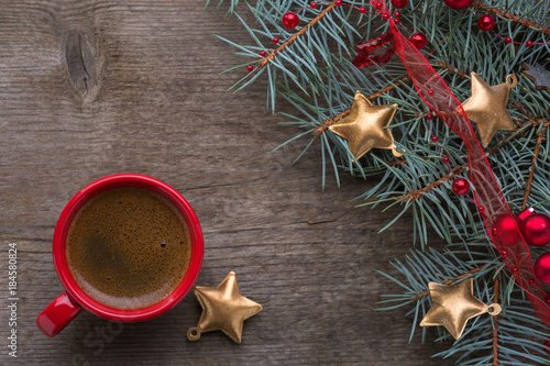  Red cup of coffee and fir branch with Christmas decorations on old wooden  background.