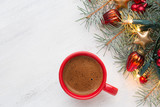 Cup of coffee and fir branch with  Christmas decorations and glowing garland on old wooden shabby background with empty space for text.