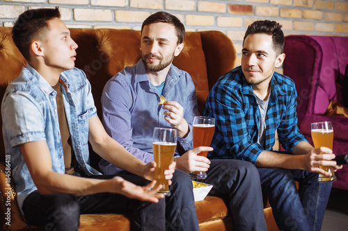 Friendship, sports and entertainment concept - happy male friends with beer watching tv at home.