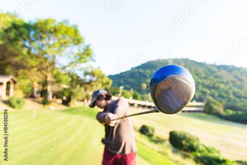 man golf player at downswing after hit golf ball away from tee off to the fairway